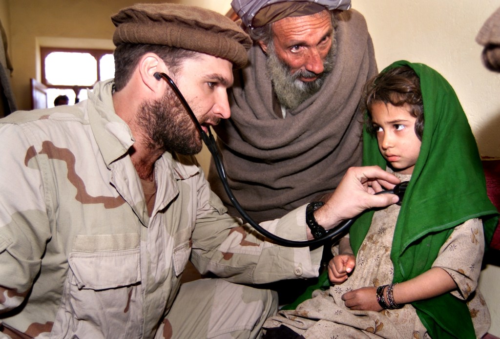 SGM Randy Surles in Afghanistan in 2003, rendering medical attention to an Afghan child.